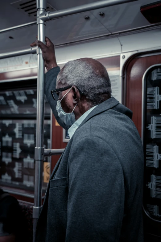 a man stands in the subway while wearing a mask