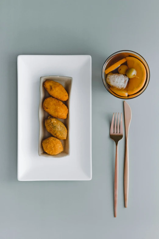 a bowl of donuts, a fork and spoon on a table