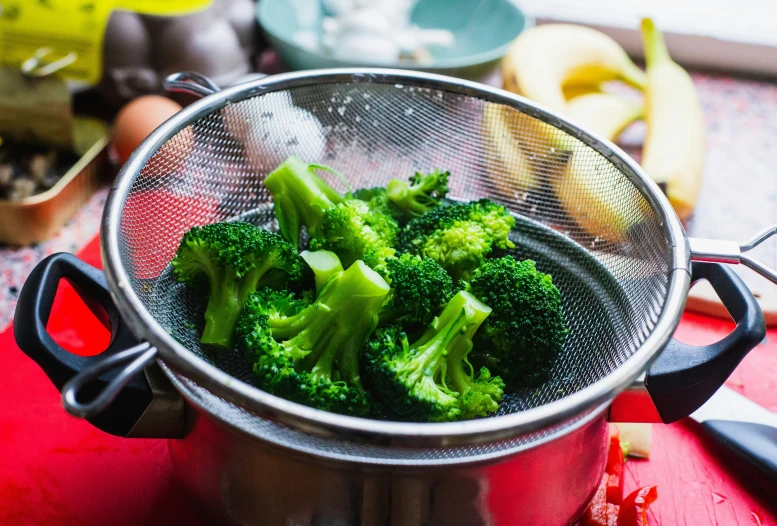 broccoli that is being cooked in a strainer