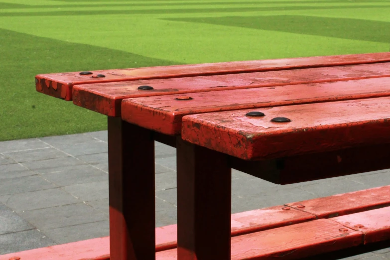 a red bench with a green and baseball field in the background