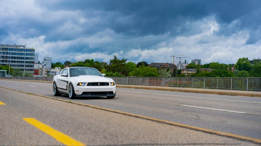 a white sports car traveling down a road next to tall buildings