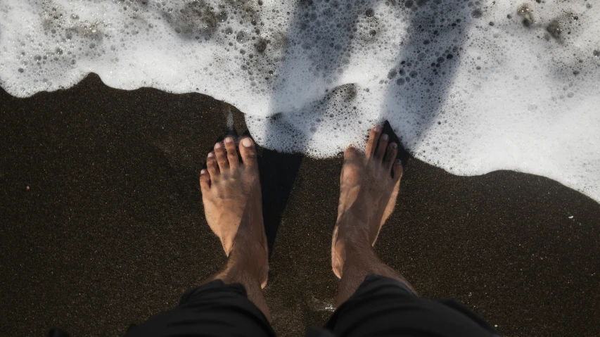 the feet of a person who is standing in the sand