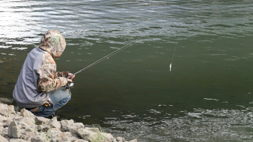 man on the rocks fishing in a lake