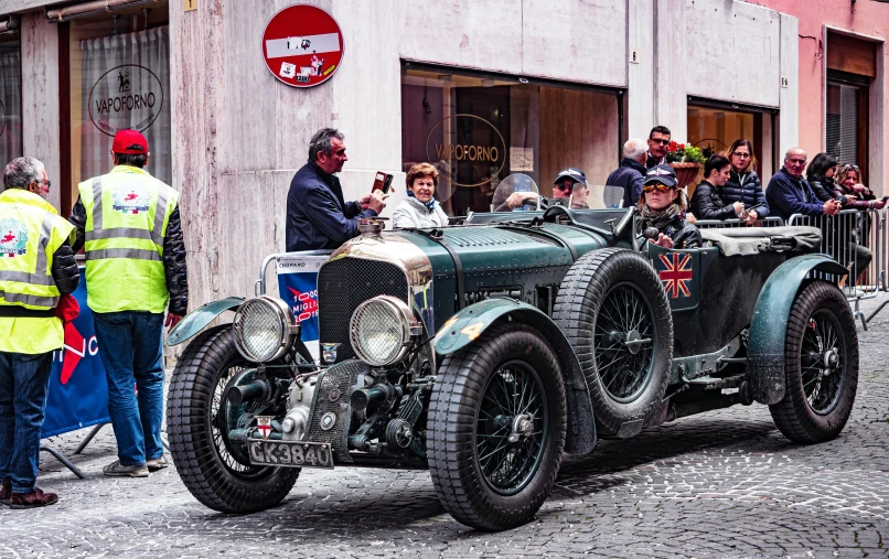 a group of people gather around an antique race car