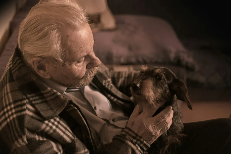 an older man holding his dog with both hands