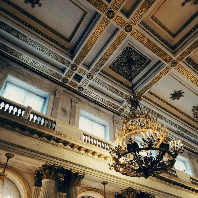 large chandelier hanging in ornate ceiling with pillars and windows