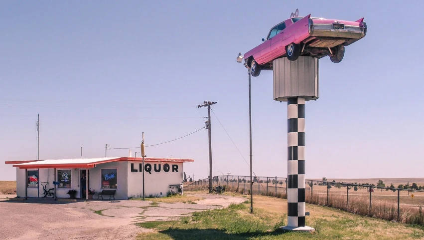 an upside down car sculpture sits outside the station