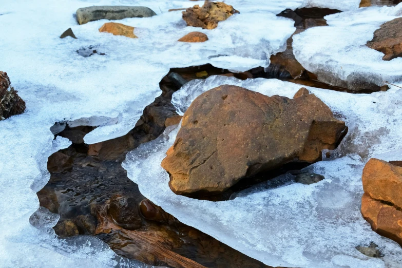 some very pretty rocks and snow by a river