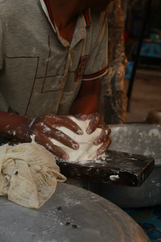 a man wearing gloves on his hands preparing doughnuts