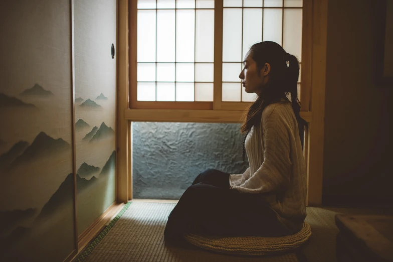 a woman sitting in a meditation room in front of a door