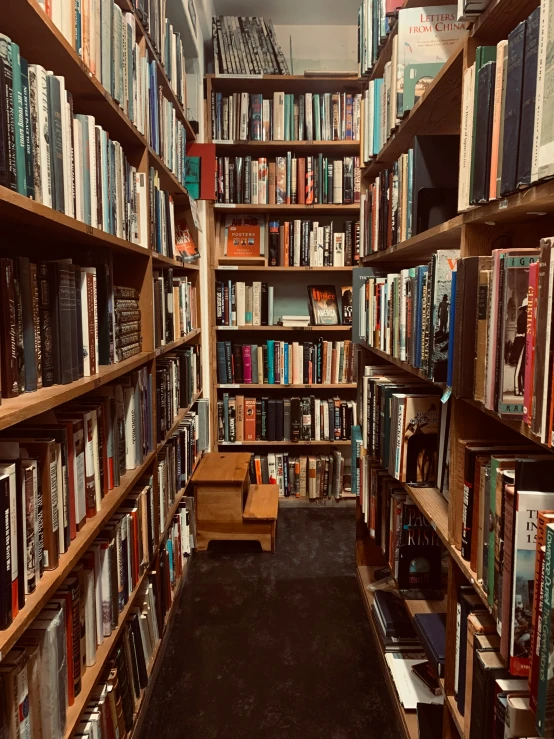 a book filled bookshelf next to a walkway with dark carpet