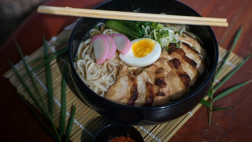 a black bowl filled with ramen and an egg on top