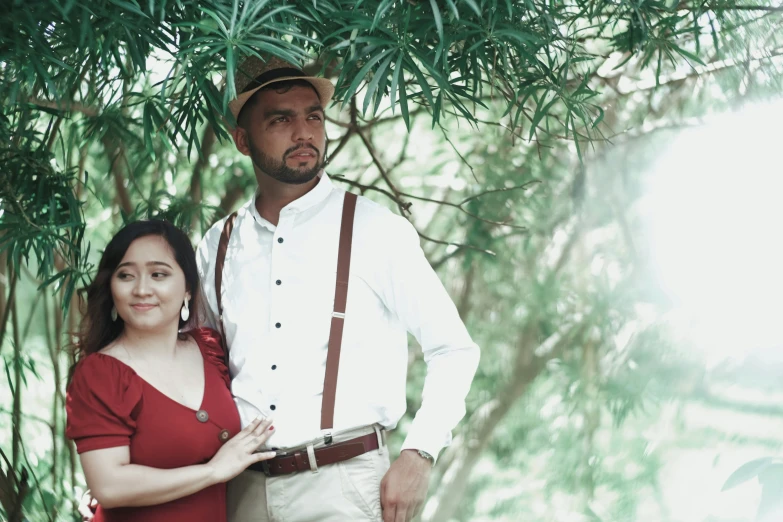 a man and woman standing under a tree in the sunlight