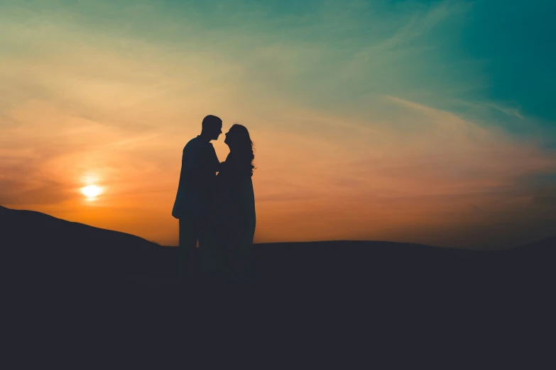 silhouetted man and woman near sunset over desert