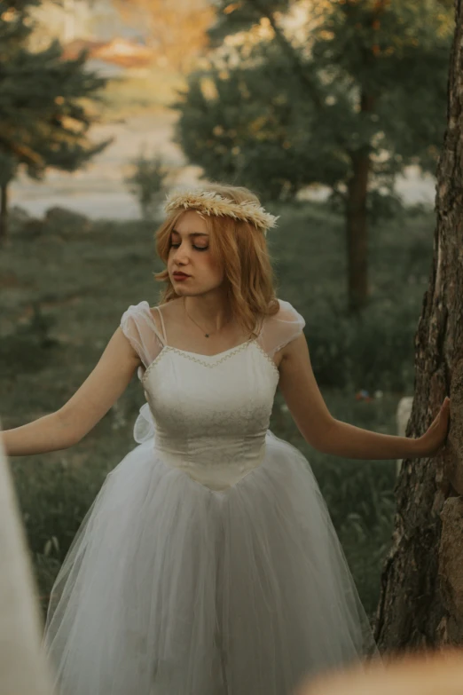 a woman in a white wedding gown standing near a tree