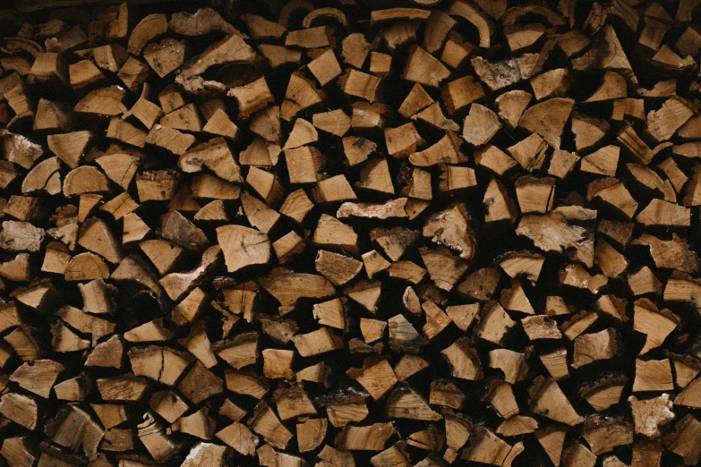 a large pile of chopped firewood with one fire on the ground