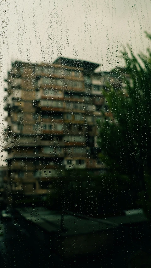 rain drops falling off of a window in the distance