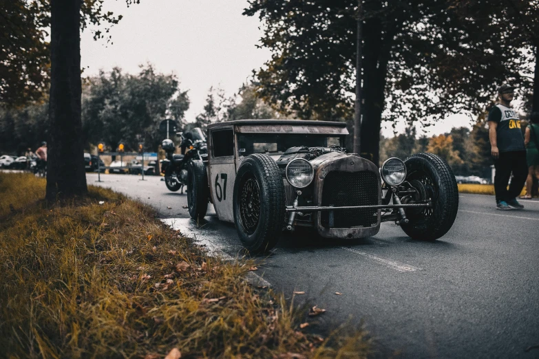 a classic vehicle driving down the road next to trees