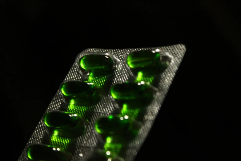 a close up view of green pills on a black background