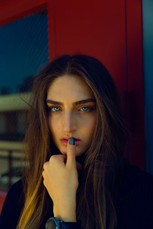 a woman with long brown hair holding her finger up to her index