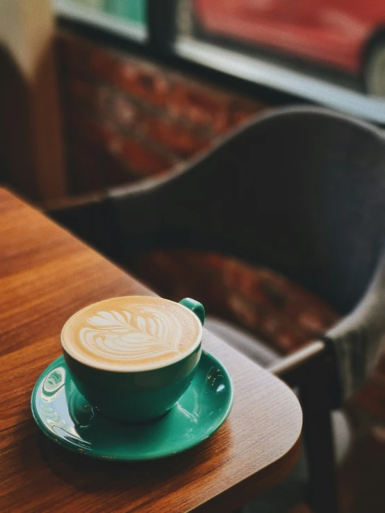 a cup of cappuccino sitting on a wooden table