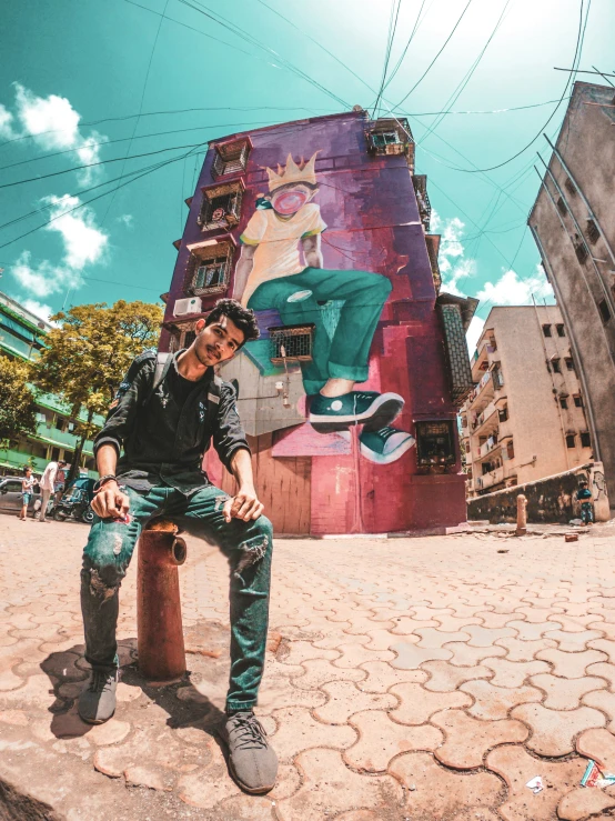 a man sitting on top of a fire hydrant next to graffiti