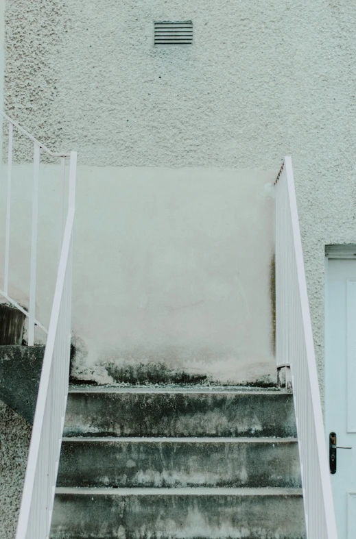 a concrete staircase leads down to a white door