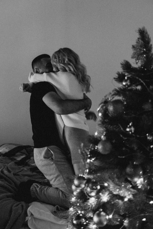 a couple hug in front of the christmas tree