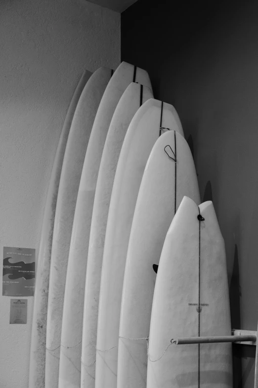 five long surfboards standing up against a wall