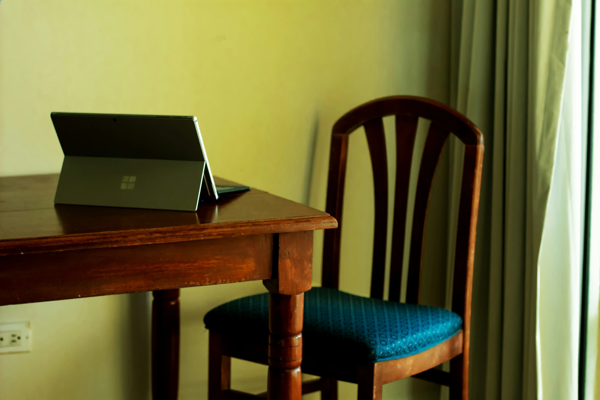 an empty chair sitting next to a desk with an open laptop