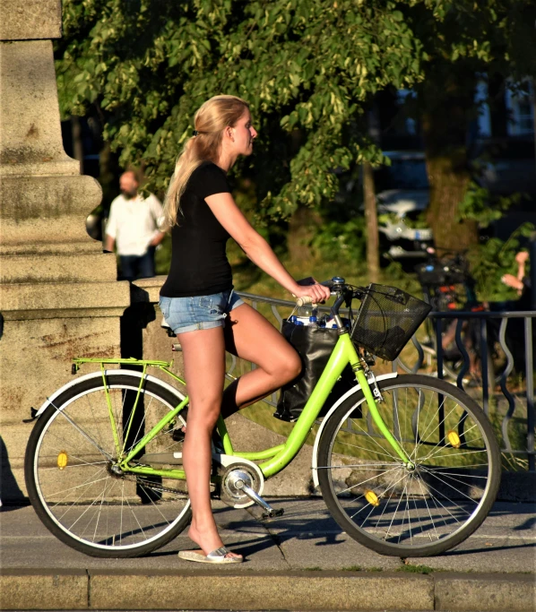 a girl riding on the back of a green bicycle