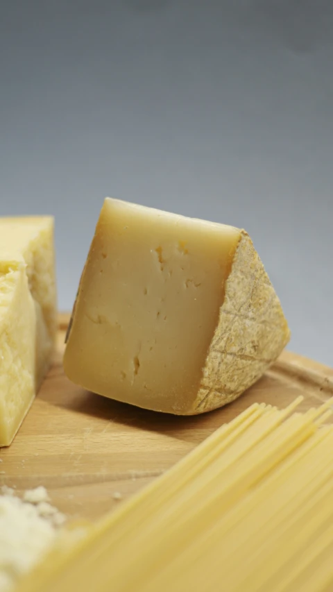 pieces of cheese sitting on top of a wooden  board