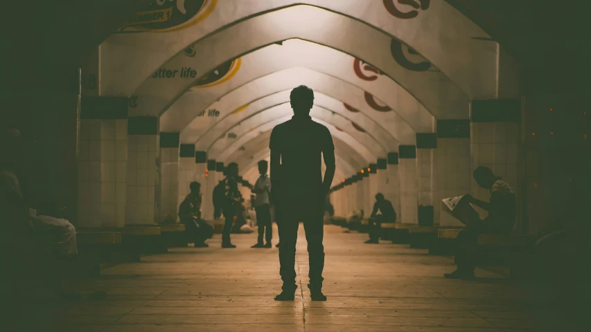 a man is standing alone in the middle of the subway