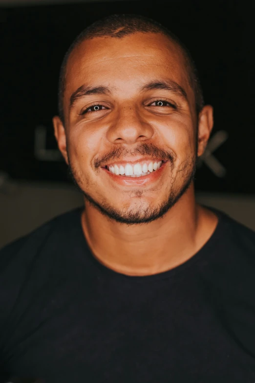 a man smiling at the camera in front of a sign