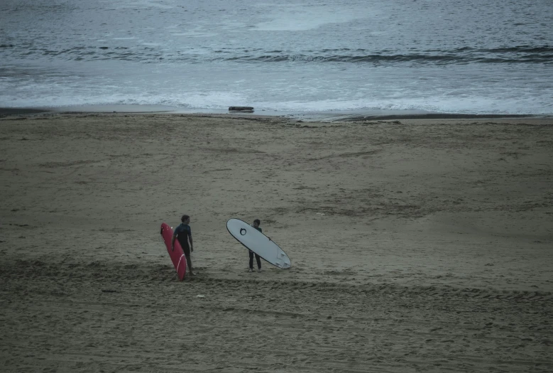 two people with surfboards walking towards the ocean