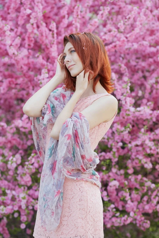 the woman is talking on the phone outside in front of a pink flower bush