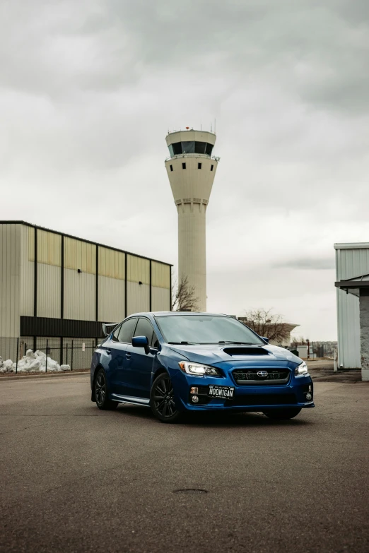 a blue subaruce parked near a passenger gate and an airport control tower