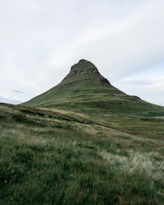 a small hill that is surrounded by green grass