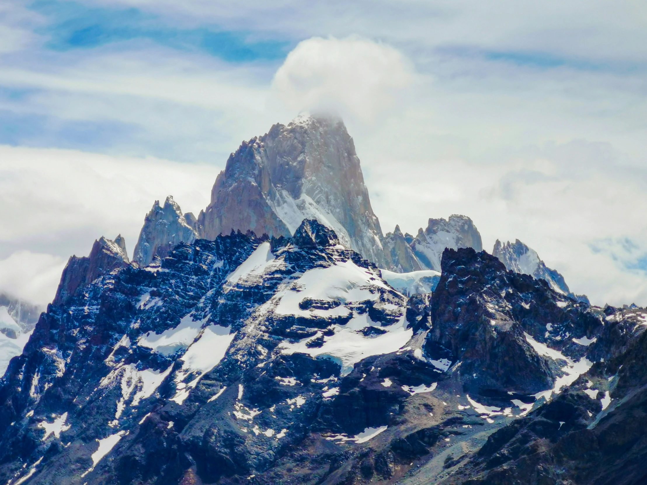 a large mountain peak that is snow covered in clouds