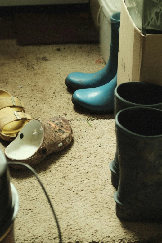 blue boots are sitting on the floor next to a cup