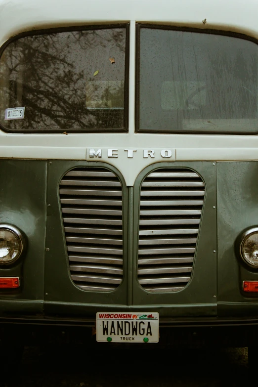 a green, long, abandoned metro van parked by the curb