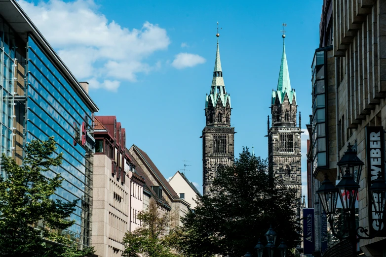 two tall buildings surrounded by trees near buildings