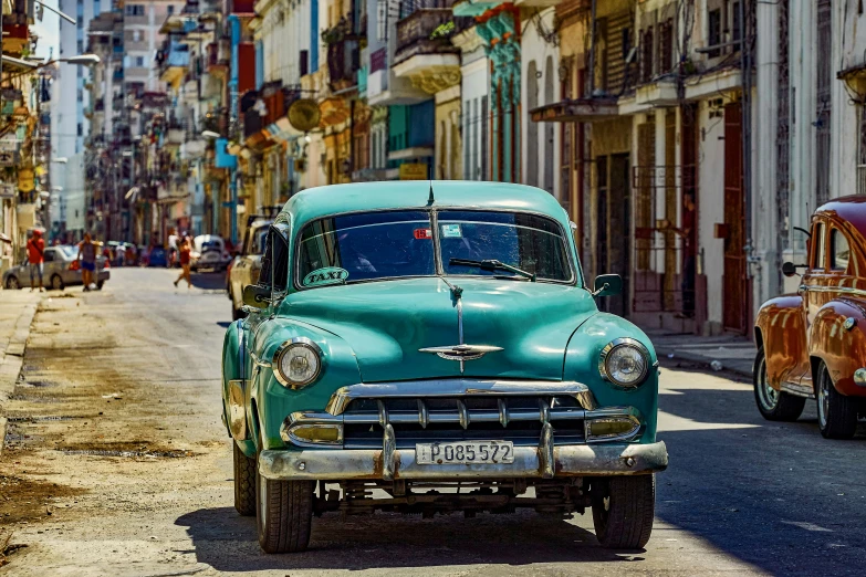 an old fashioned green car sitting on the side of a road