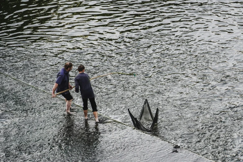 two people holding up a broken umbrella over water