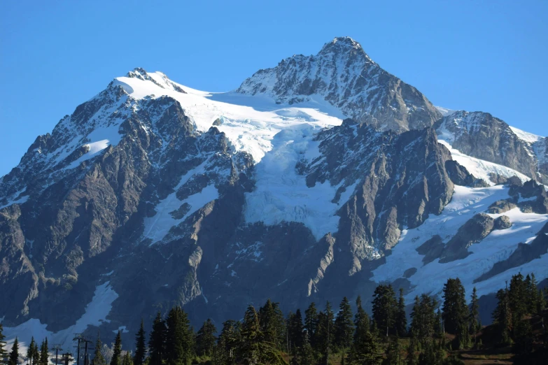 a very tall snow covered mountain with lots of trees