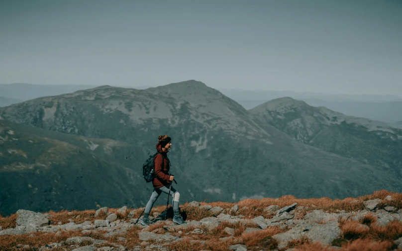 a person walking along side the mountains carrying his backpack