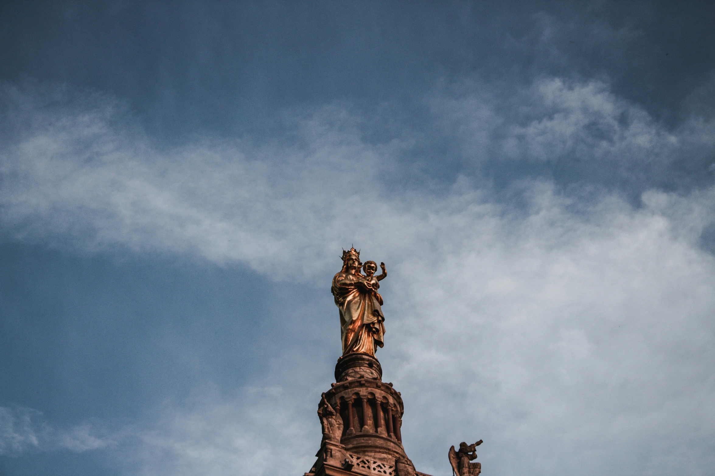 a tall building with a clock and spire and statue on top