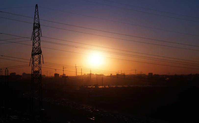 the sun is setting behind a wire tower