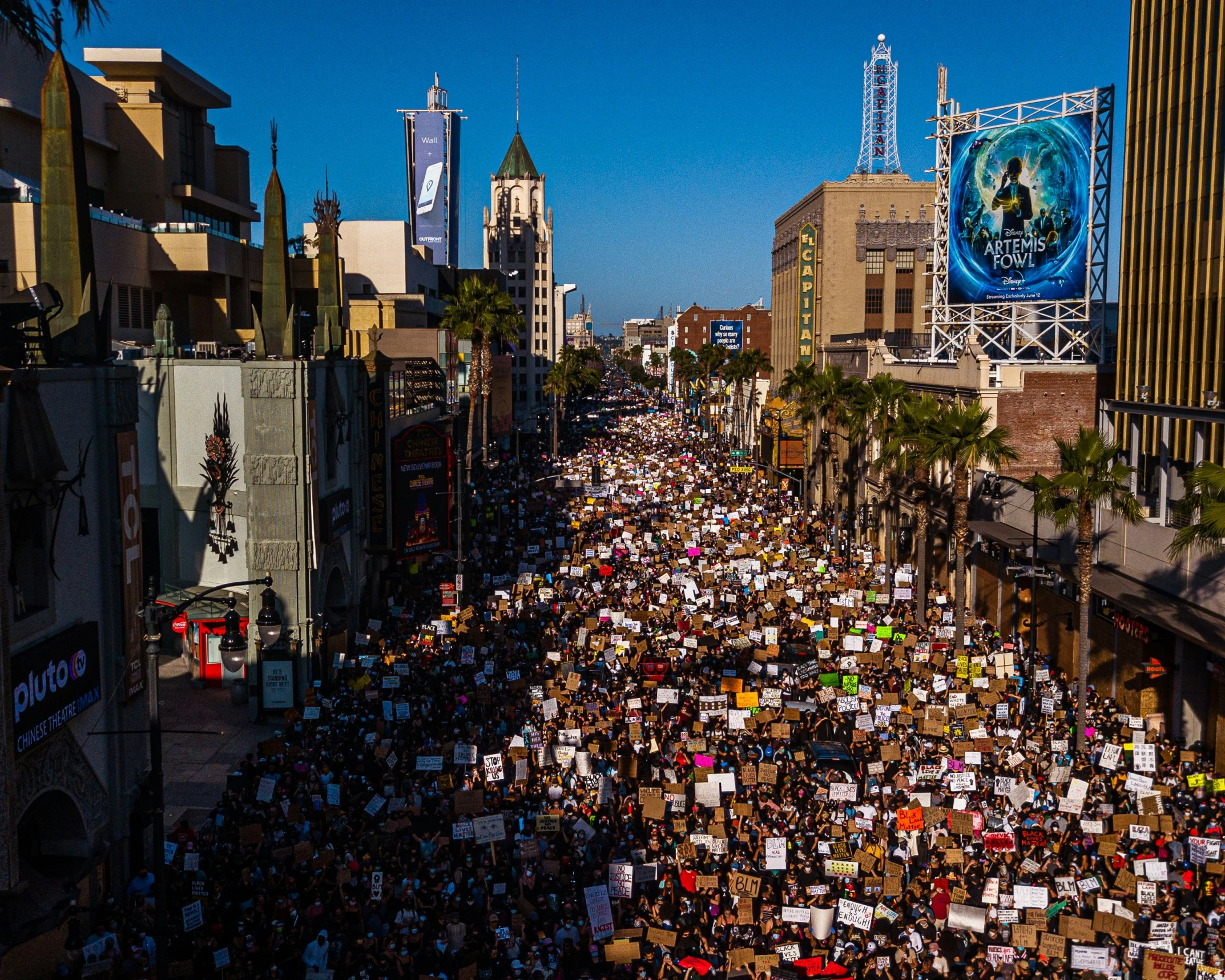 a crowded street has lots of people, signs and billboards on it