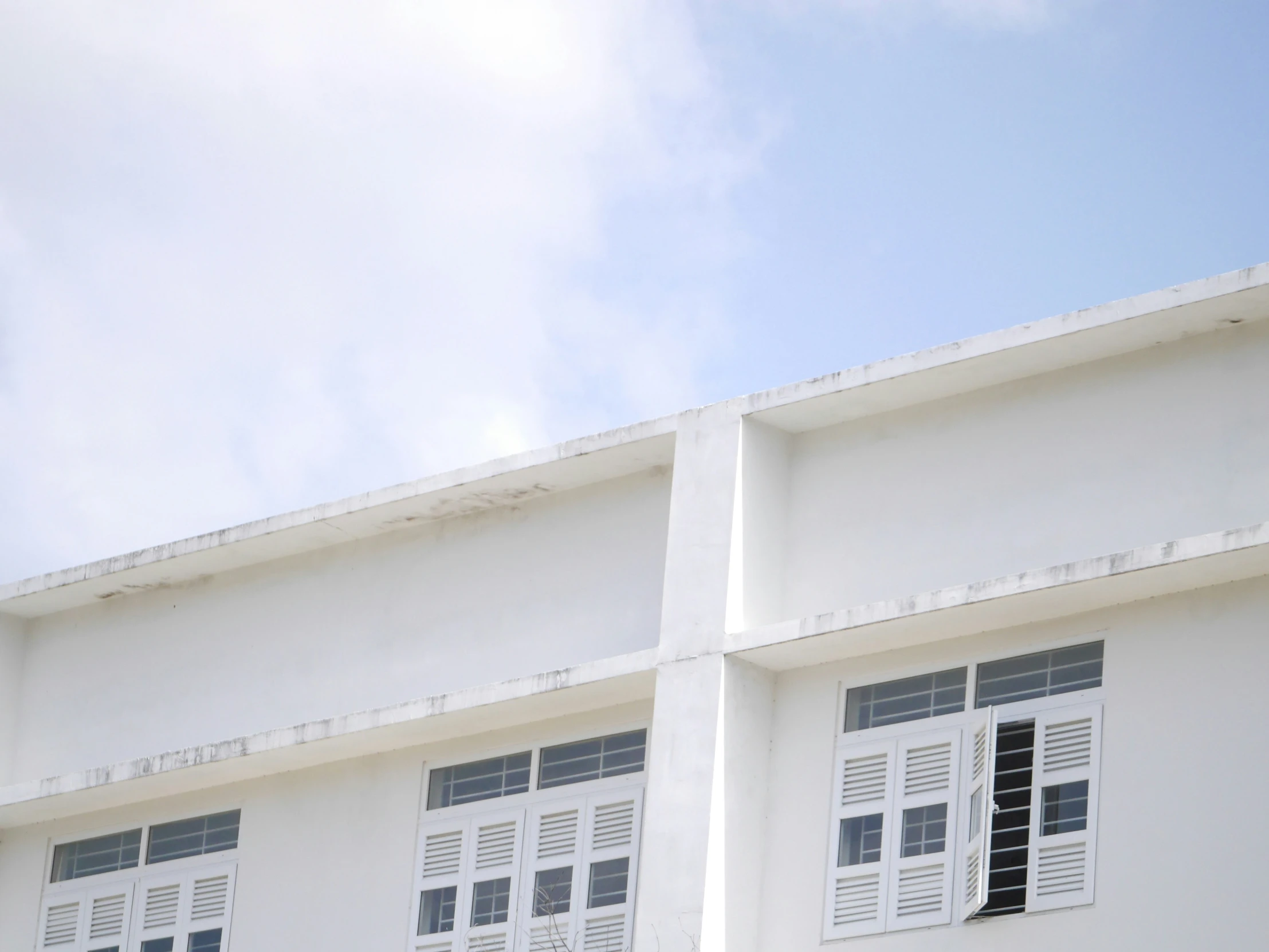 a couple of buildings that are white and one has windows with the windows open